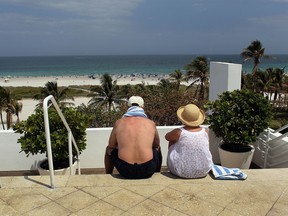 A couple looks out on the beach in Miami Beach, Florida.